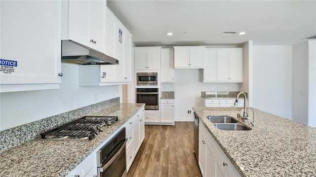 kitchen with white cabinetry, stainless steel appliances, sink, hardwood / wood-style flooring, and light stone counters