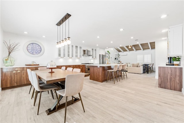 dining area with lofted ceiling with beams and light hardwood / wood-style flooring