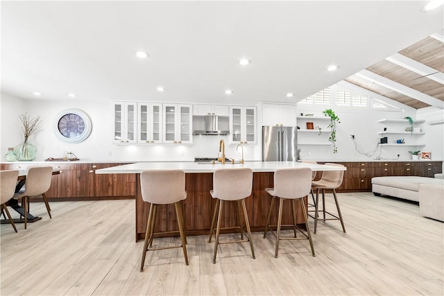 kitchen with white cabinetry, a kitchen breakfast bar, a large island, light wood-type flooring, and high end refrigerator