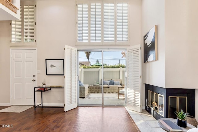 doorway to outside with a towering ceiling, hardwood / wood-style flooring, and a multi sided fireplace