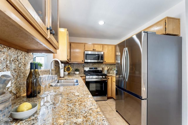 kitchen with sink, light tile patterned floors, backsplash, stainless steel appliances, and light stone countertops