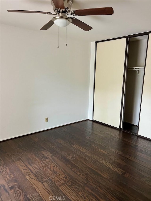 unfurnished bedroom featuring dark hardwood / wood-style floors, ceiling fan, and a closet