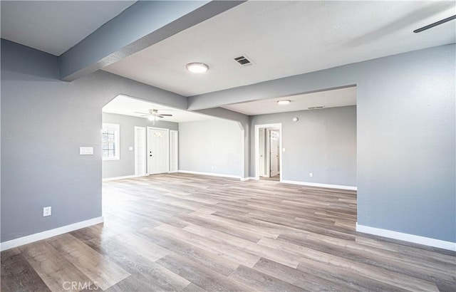 spare room featuring ceiling fan, beamed ceiling, and light wood-type flooring