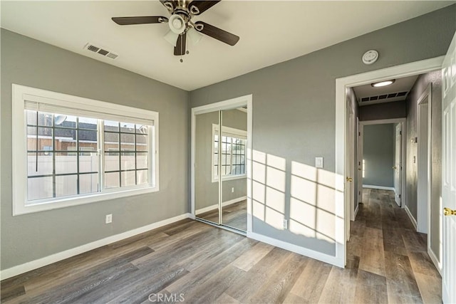 unfurnished bedroom featuring ceiling fan, dark hardwood / wood-style floors, and a closet