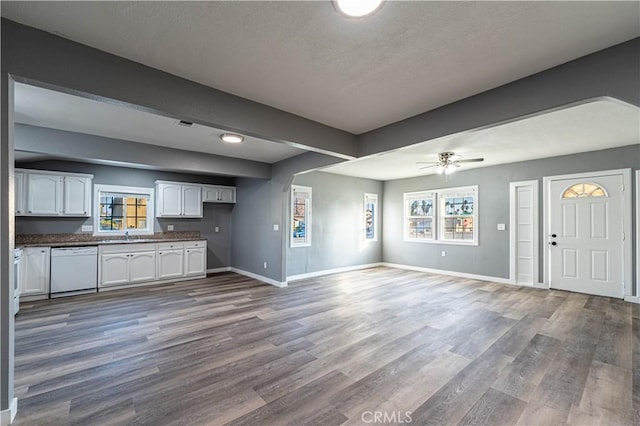 unfurnished living room featuring ceiling fan, dark wood-type flooring, and plenty of natural light