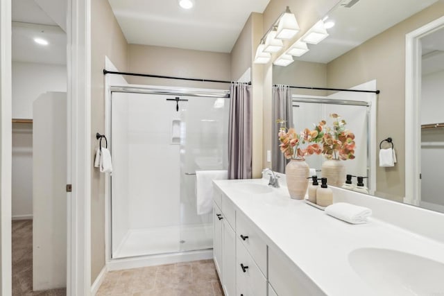 bathroom featuring a shower with door and vanity