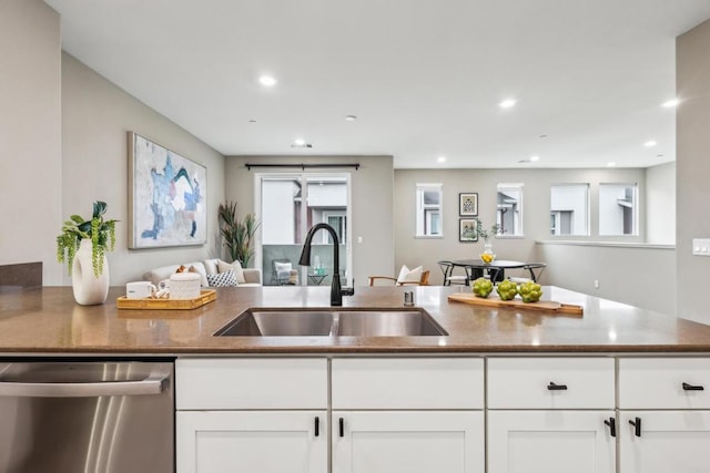 kitchen with sink, stainless steel dishwasher, white cabinets, and dark stone countertops