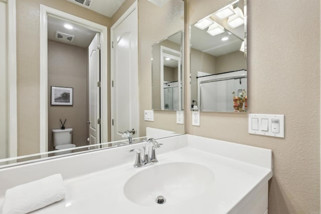 bathroom with sink, toilet, and an enclosed shower