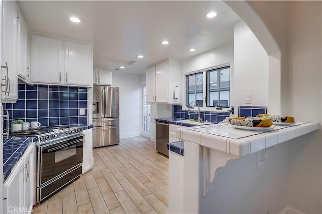 kitchen featuring white cabinetry, tile countertops, stainless steel appliances, and tasteful backsplash