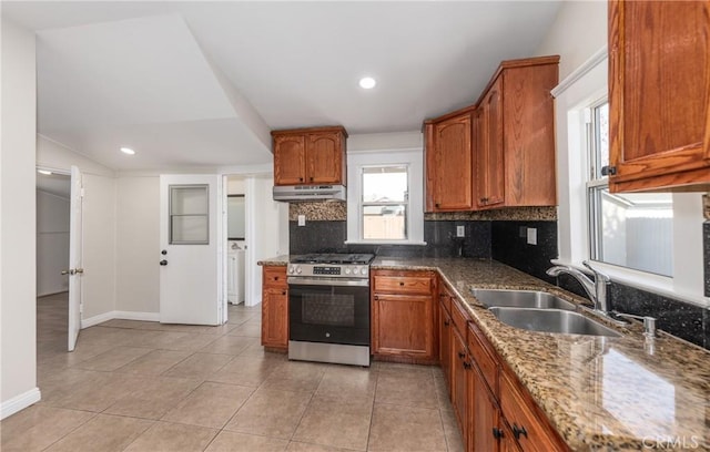 kitchen featuring light tile patterned floors, sink, separate washer and dryer, stainless steel range with gas stovetop, and stone countertops