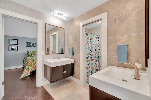 bathroom featuring vanity, curtained shower, tile walls, and a textured ceiling