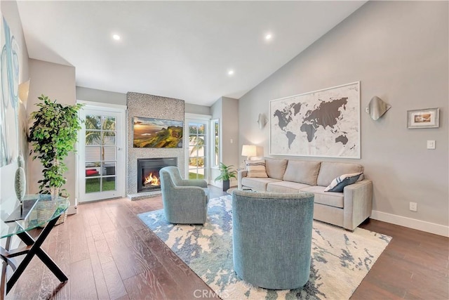 living room featuring vaulted ceiling, dark hardwood / wood-style flooring, and a fireplace