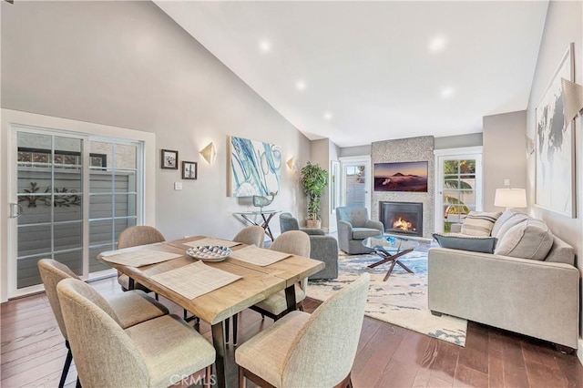 dining area with high vaulted ceiling, dark hardwood / wood-style floors, and a fireplace