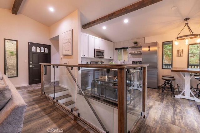 kitchen featuring white cabinets, appliances with stainless steel finishes, decorative backsplash, dark hardwood / wood-style floors, and lofted ceiling with beams