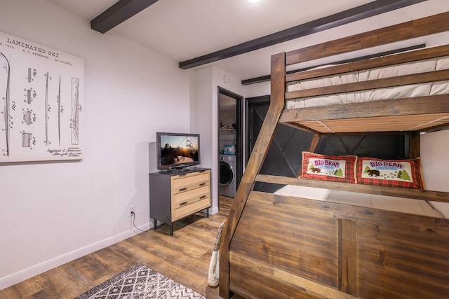 bedroom with beamed ceiling, washer / dryer, and hardwood / wood-style floors