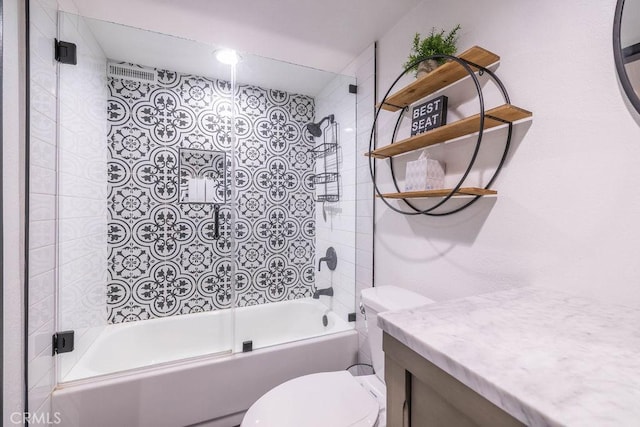 full bathroom with bath / shower combo with glass door, toilet, and vanity