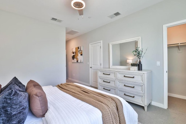 carpeted bedroom with ceiling fan, a spacious closet, and a closet