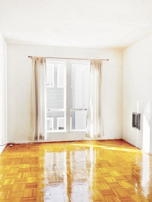 spare room featuring light parquet floors, a wealth of natural light, and heating unit