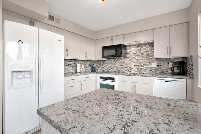 kitchen featuring backsplash, white appliances, and white cabinets