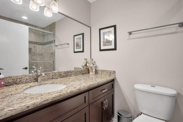 bathroom with toilet, a shower with door, and vanity