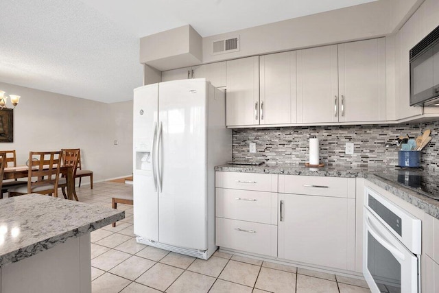 kitchen featuring black appliances, light stone countertops, white cabinetry, light tile patterned floors, and backsplash