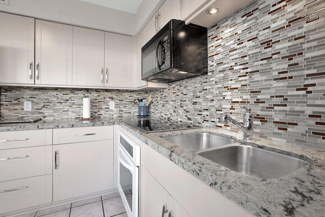 kitchen featuring black appliances, white cabinetry, sink, backsplash, and light tile patterned floors