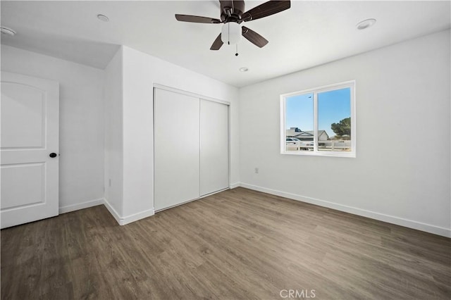 unfurnished bedroom with dark wood-type flooring, a closet, and ceiling fan