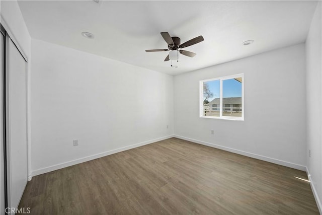 unfurnished bedroom with ceiling fan, dark wood-type flooring, and a closet