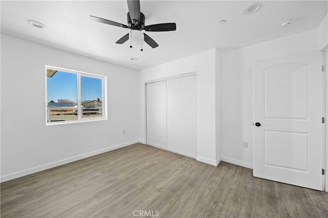 unfurnished bedroom featuring light wood-type flooring, a closet, and ceiling fan