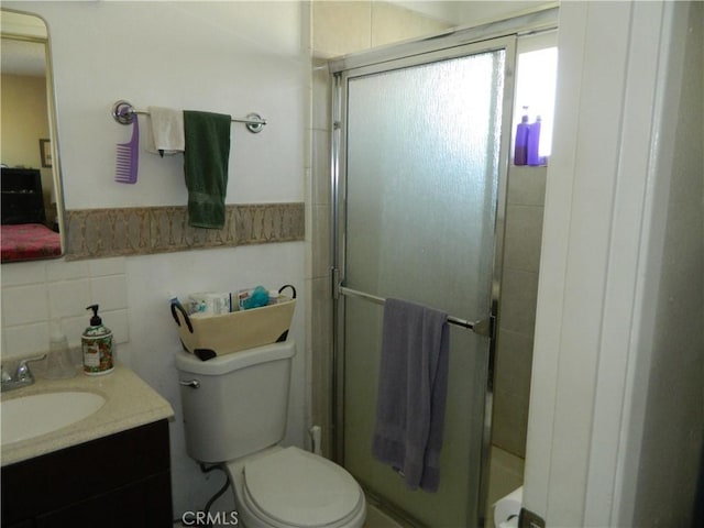 bathroom with toilet, tile walls, walk in shower, and vanity