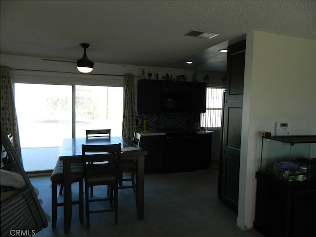 dining area with a wealth of natural light, a textured ceiling, and carpet flooring