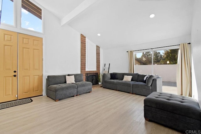 living room with light hardwood / wood-style flooring, beam ceiling, high vaulted ceiling, and a brick fireplace