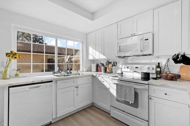 kitchen featuring sink, white appliances, light hardwood / wood-style flooring, and white cabinets