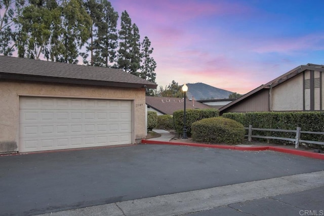 garage at dusk featuring a mountain view