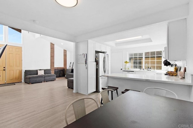 dining room featuring a tray ceiling, light hardwood / wood-style flooring, lofted ceiling, and a fireplace