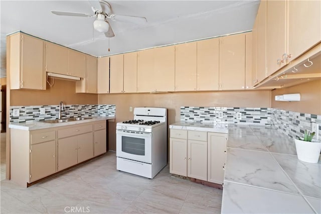 kitchen with sink, white range with gas cooktop, backsplash, and cream cabinets