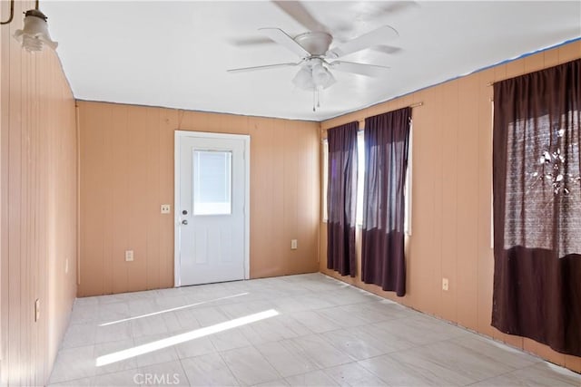 unfurnished room featuring ceiling fan and wooden walls