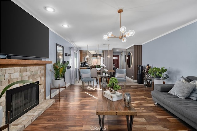 living room featuring a chandelier, a stone fireplace, crown molding, and dark hardwood / wood-style floors