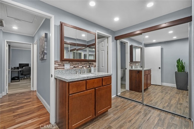 kitchen with sink, ornamental molding, tasteful backsplash, and wood-type flooring