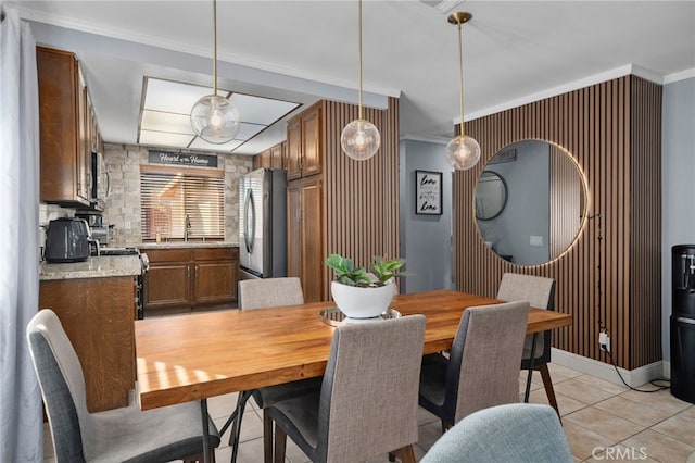 dining space featuring sink, crown molding, and light tile patterned flooring