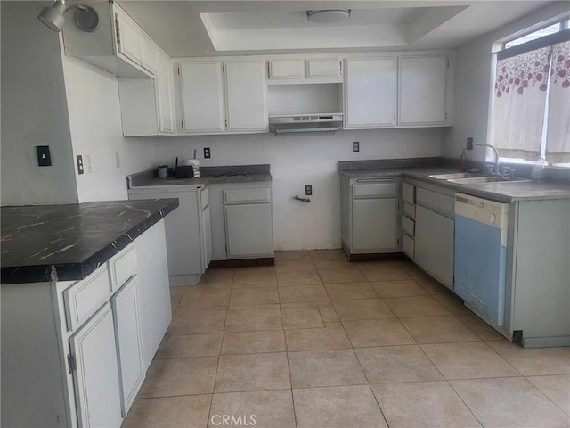 kitchen featuring sink, white cabinets, light tile patterned floors, white dishwasher, and a tray ceiling