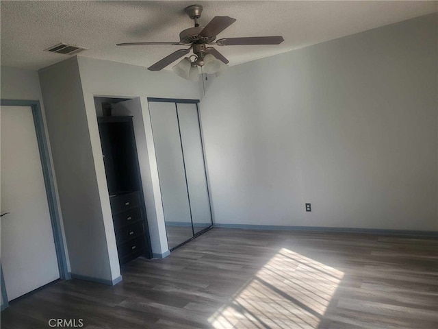 unfurnished bedroom with ceiling fan, dark wood-type flooring, a closet, and a textured ceiling