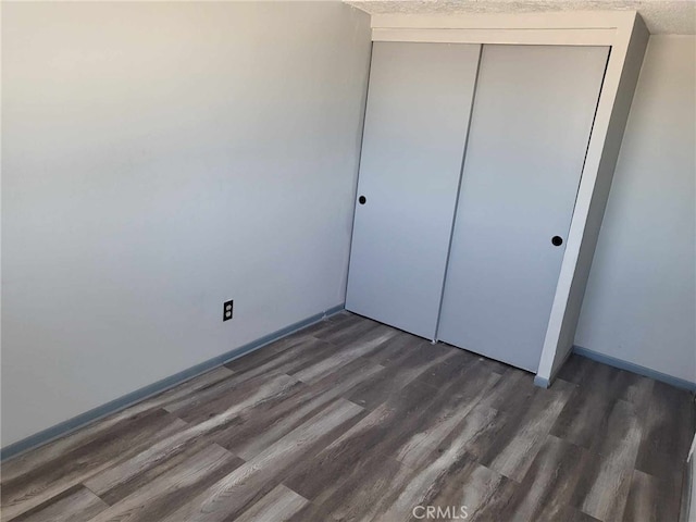 unfurnished bedroom with a closet and dark hardwood / wood-style floors