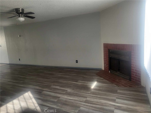 unfurnished living room featuring ceiling fan, dark hardwood / wood-style floors, a textured ceiling, and a fireplace