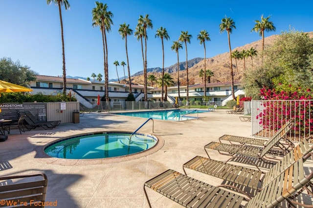 view of swimming pool featuring a mountain view, a patio area, and a community hot tub