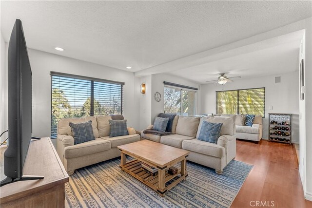 living room with ceiling fan, dark wood-type flooring, and a textured ceiling