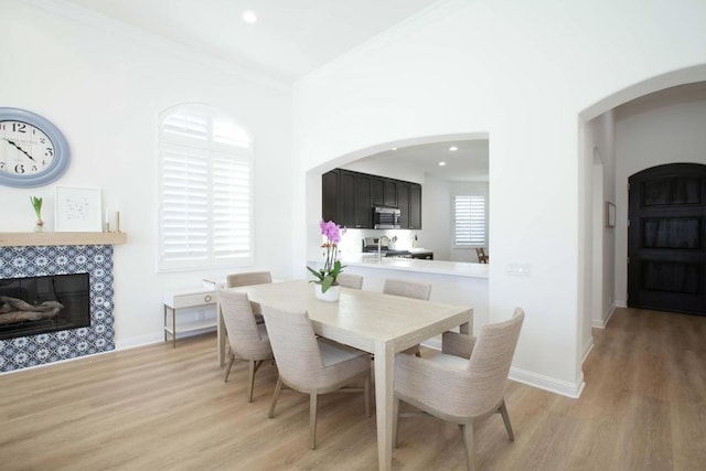 dining space with ornamental molding, a fireplace, and light hardwood / wood-style flooring