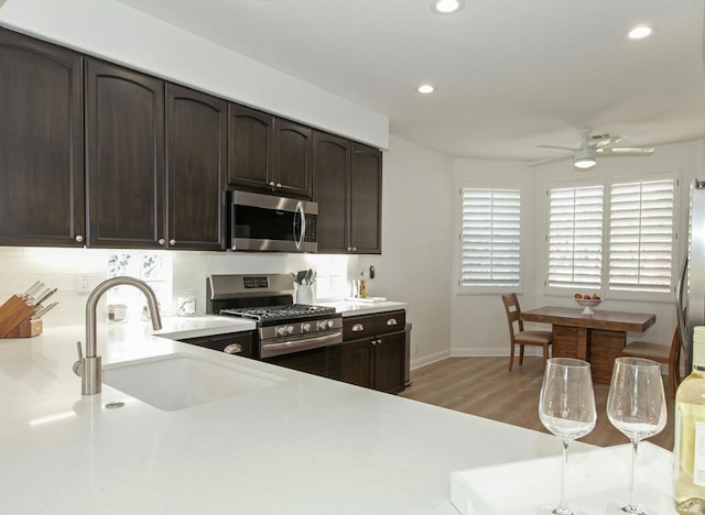 kitchen featuring dark brown cabinets, stainless steel appliances, sink, and wood-type flooring