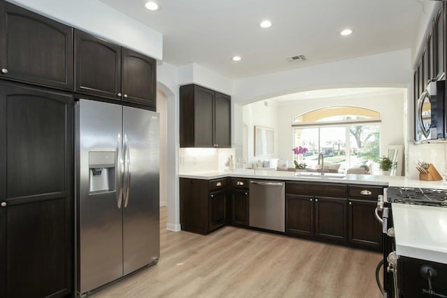 kitchen featuring sink, appliances with stainless steel finishes, tasteful backsplash, dark brown cabinetry, and light wood-type flooring