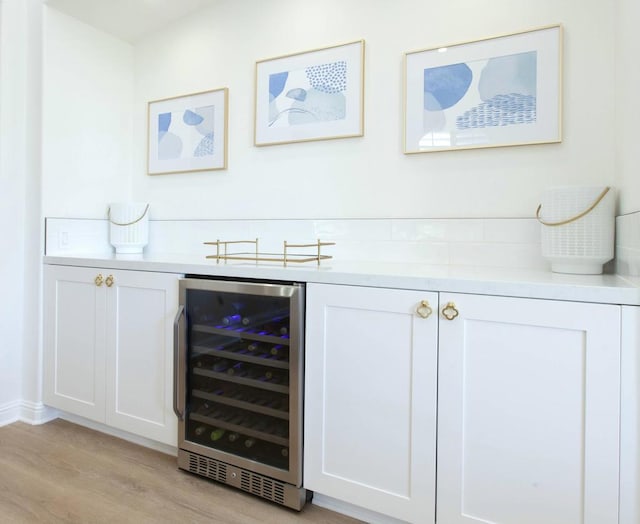 bar featuring wine cooler, light hardwood / wood-style flooring, and white cabinets